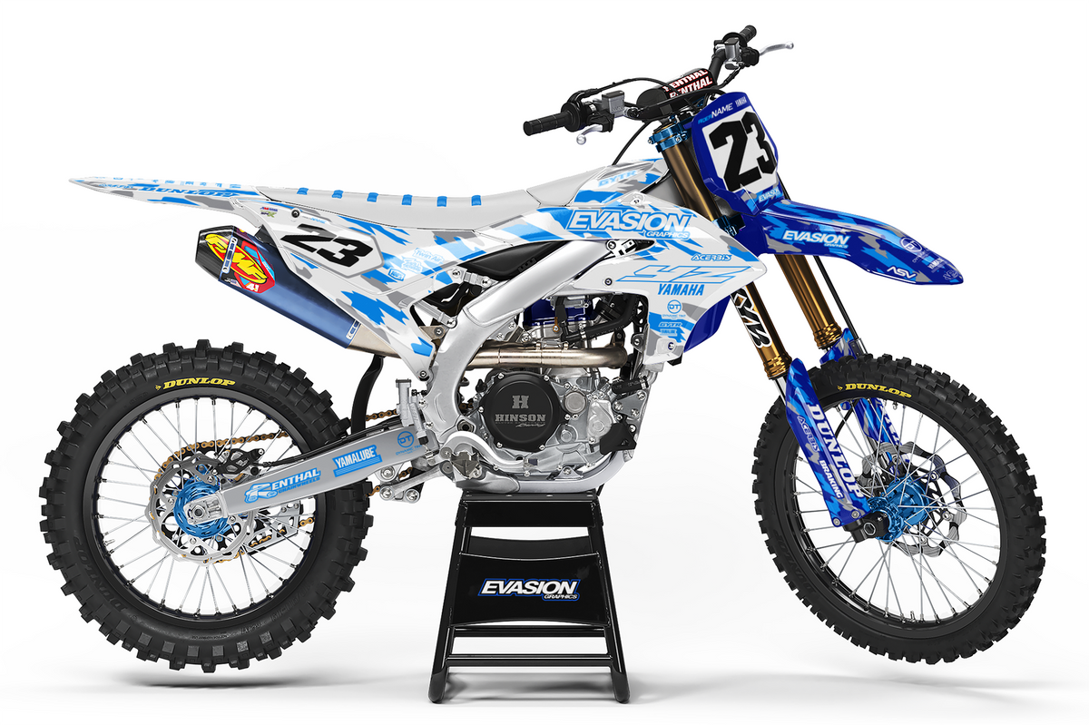 A blue and white camo yamaha dirt bike with number 23, displayed on a black stand against a white studio background.